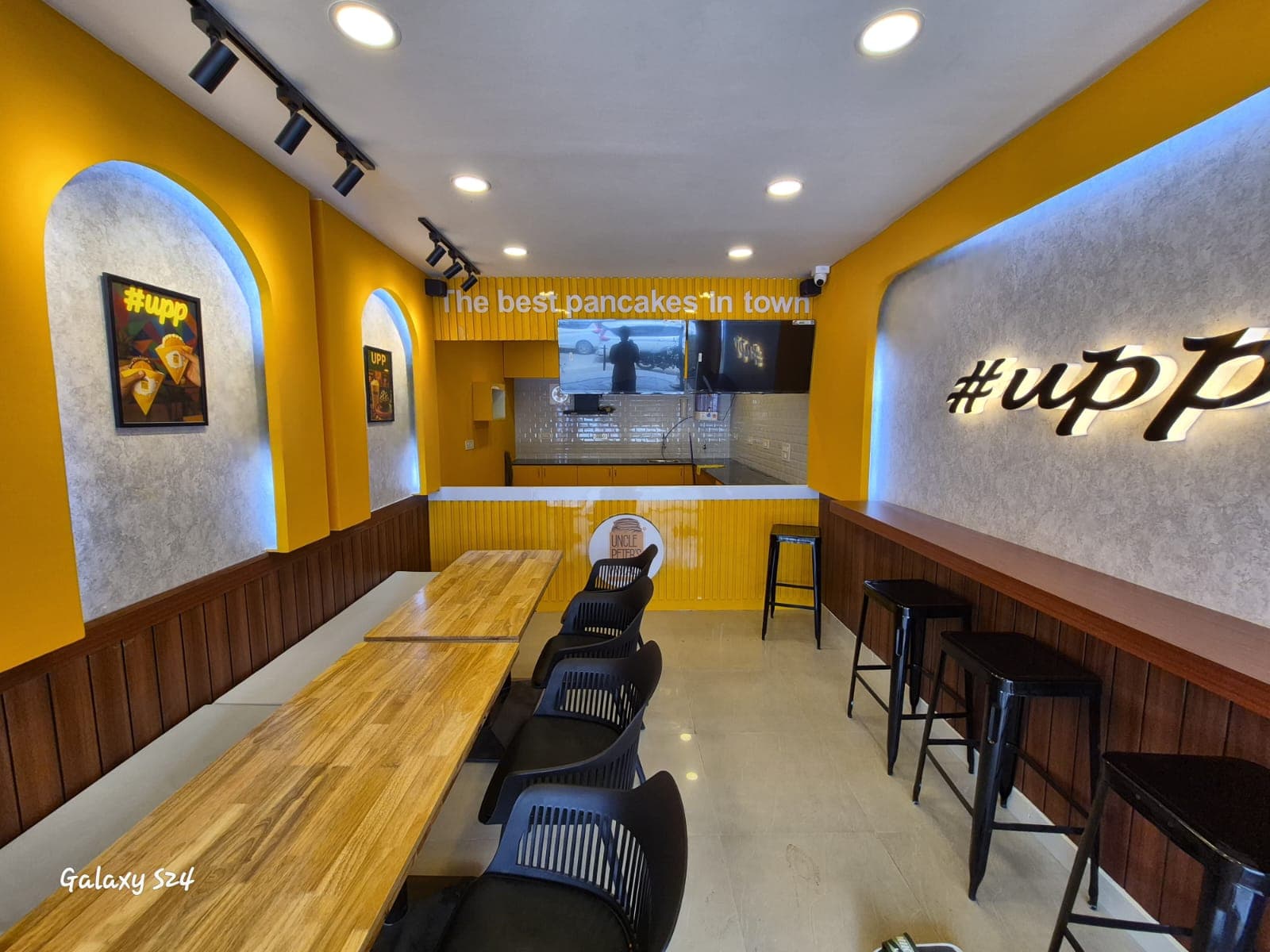 Uncle Peter's Pancakes seating area with CCTV camera and wall-mounted screens